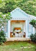 A private bungalo with blue exterior surrounded by lush greenery.